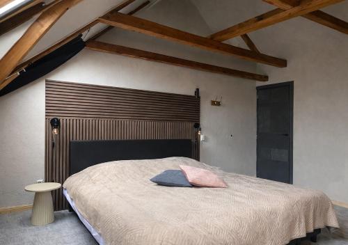 a bedroom with a large bed with a wooden headboard at Het Ambachtshuis Warffum in Warffum
