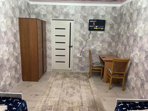 een kamer met een bureau, een tafel en een deur bij Nur Hotel in Karakol