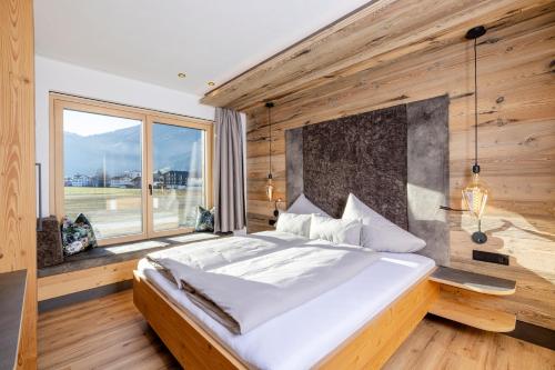 a bedroom with a large bed and a large window at my Zillernest in Zell am Ziller