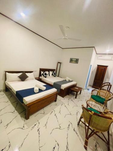 a bedroom with two beds and a chair in it at Jasmine Villa in Bentota