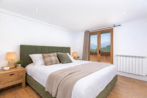 een slaapkamer met een groot bed en een raam bij Appartements dans le Chalet Nessa - Combloux in Combloux