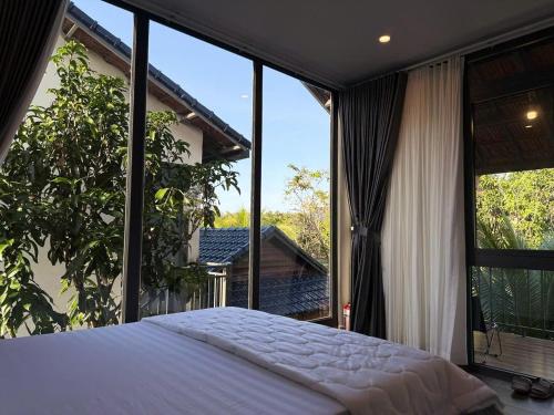 a bedroom with a bed and large glass windows at Coco Retreat in Tân Phú