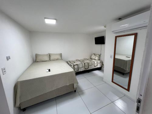 a white room with a bed and a mirror at Flats Brisa Antunes in Maragogi