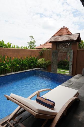 a lounge chair next to a swimming pool at Nauna Villa Bali in Ubud
