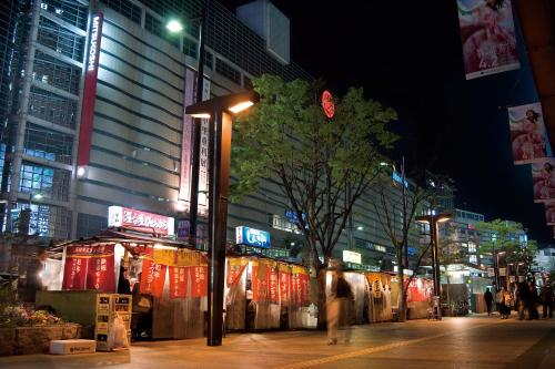 a city street at night with people walking on the sidewalk at Seaside Hotel Twins Momochi in Fukuoka