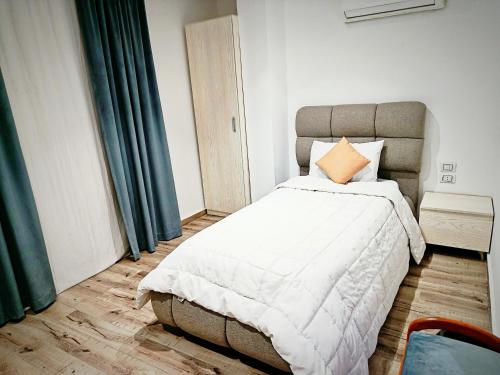 een slaapkamer met een groot wit bed en een oranje kussen bij Pyrs Giza Heaven in Caïro