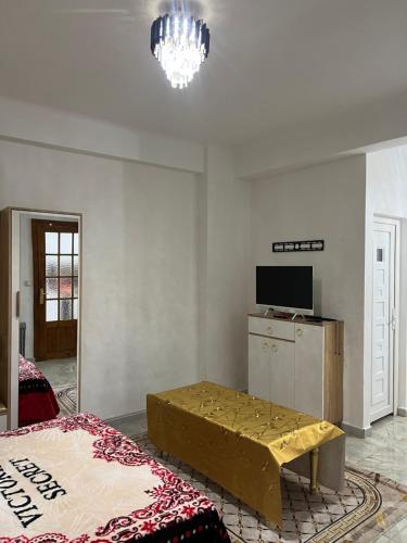 un soggiorno con un letto, un tavolo e una televisione di Magnifique Studio a Mostaganem