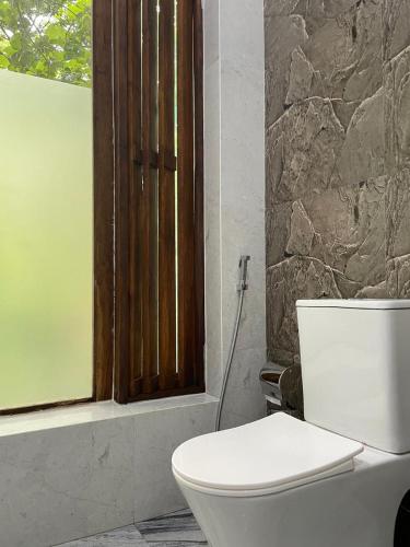 a bathroom with a white toilet and a window at Sigiriya Hotel and Resort in Sigiriya