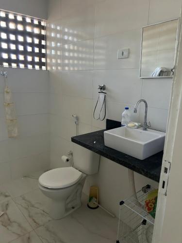 a white bathroom with a sink and a toilet at Casa ampla e completa a poucos passos da praia! in Itamaracá