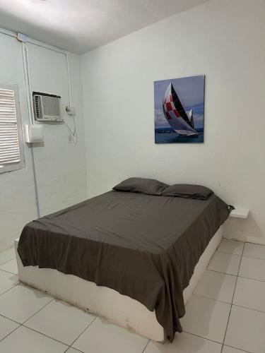 a bedroom with a bed with a painting on the wall at Casa ampla e completa a poucos passos da praia! in Itamaracá