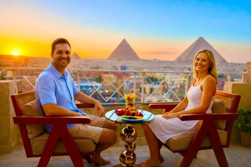 Een man en een vrouw zitten op een balkon met uitzicht op de piramides. bij Zoom Pyramids View inn in Caïro