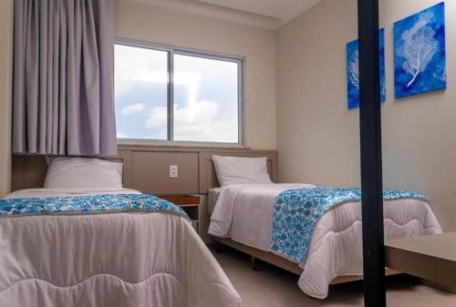 ein Schlafzimmer mit zwei Betten und einem Fenster in der Unterkunft Casa de Praia Atalaia in Salinópolis