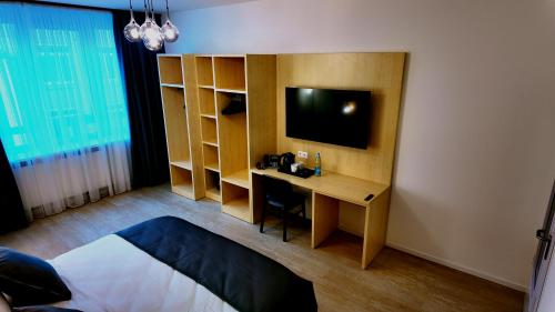 - une chambre avec un bureau, une télévision et un lit dans l'établissement Niko Hotel am Hannover Hbf, à Hanovre