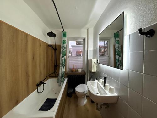 een badkamer met een wastafel, een bad en een toilet bij Hotel Mühlental in Wernigerode