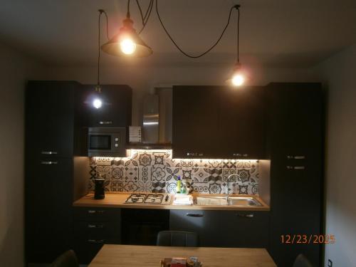 una cucina con armadi neri, lavandino e luci di Residence ai fiori - Simone Apartment ad Arta Terme