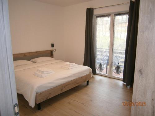 una camera da letto con un letto e una grande finestra di Residence ai fiori - Simone Apartment ad Arta Terme