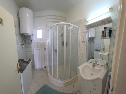 a white bathroom with a shower and a sink at Panna Ház in Jászapáti