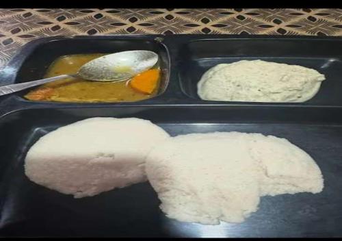 twee zwarte dienbladen met eten, waaronder rijst en andere gerechten bij MG stay in Jorhat