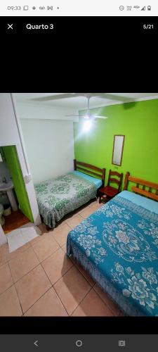 a bedroom with two beds and a green wall at Hostelval Cantinho praia do sossego in Praia Grande
