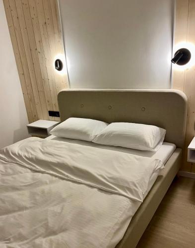 a bed with white sheets and pillows in a room at Cottages Shepit Lisu New in Myta