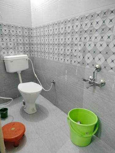 a bathroom with a toilet and a green bucket at Hotel Krishn Residency in Garwa Road