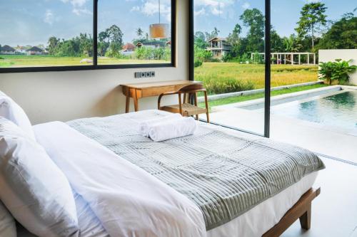 ein Schlafzimmer mit einem Bett, einem Tisch und einem Pool in der Unterkunft 2BDR Villa Aurelia - Construction nearby in Bedahulu