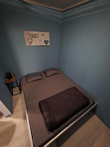 a bed in a room with a love sign on the wall at L'Orée du bois in Membre