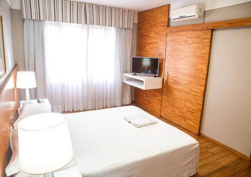 une chambre d'hôtel avec un lit et une télévision dans l'établissement Planalto Hotel, à Canoinhas