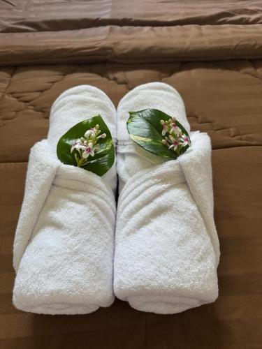 two towels with flowers on them on a bed at Rumah Cahaya Syariah Peaceful Family Home in Rampal