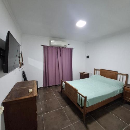 a bedroom with a bed and a purple curtain at very spacious house equipped for 4 people in Resistencia