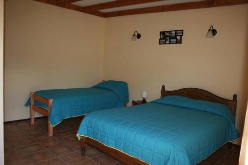 two beds in a room with blue sheets at Hostal Km Zero El Huertillo in San Pedro de Atacama