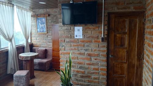 un soggiorno con parete in mattoni e TV di Hospedaje Mágico Arcángel a Ibarra