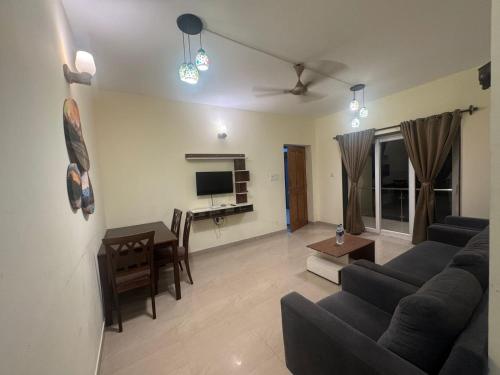 ein Wohnzimmer mit Sofa und Tisch in der Unterkunft Rosebank service Apartment in Arpora