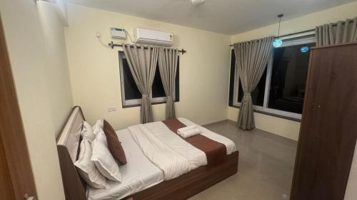 ein Schlafzimmer mit einem Bett und zwei Fenstern in der Unterkunft Rosebank service Apartment in Arpora