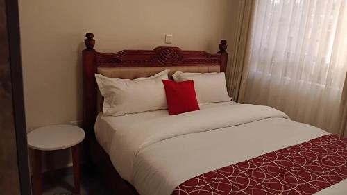 ein Schlafzimmer mit einem Bett mit einem roten Kissen in der Unterkunft Serene Stays in Naivasha