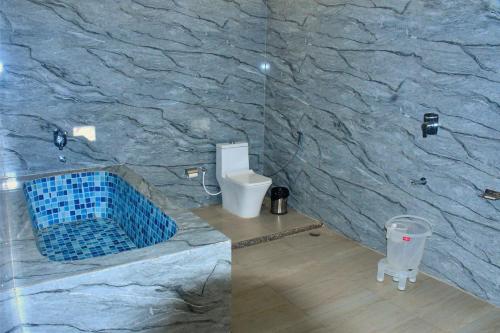 ein Badezimmer mit einer Steinwand mit einer Toilette in der Unterkunft Ranthambore Village Serai in Khilchīpur