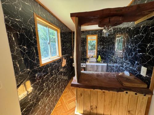 een badkamer met zwarte marmeren muren en een raam bij Cabañas Granja Paraíso in Molina