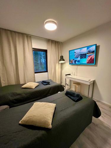 a bedroom with two beds and a tv on the wall at Modern studio apartment with free parking in Kuopio