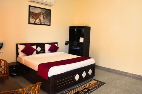 una camera da letto con un letto con cuscini rossi e bianchi di Ranthambore Village Serai a Khilchīpur