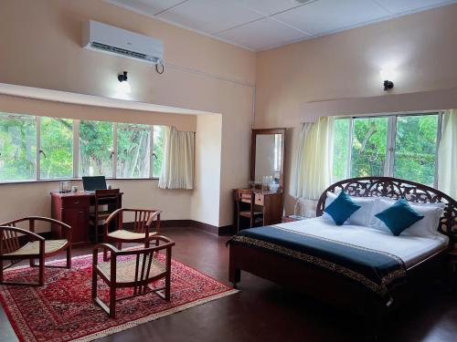 a bedroom with a bed and chairs and a desk at The Deane Residence Family Room in Colombo