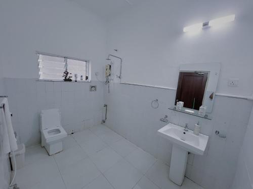 a white bathroom with a toilet and a sink at The Deane Residence Family Room in Colombo