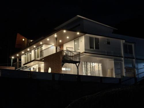 a large white house with lights on it at night at Hira Homestay in Pinangode