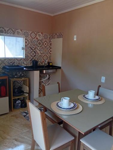 ein Esstisch mit zwei Tassen und Tellern darauf in der Unterkunft Cozy house in Matariz Beach in Angra dos Reis