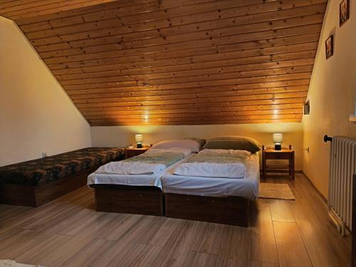 een slaapkamer met twee bedden en een houten plafond bij Chata Kubko in Bobrovník