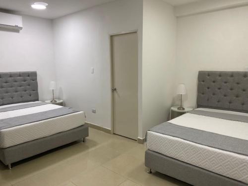 a bedroom with two beds and a door to a door at Apartahotel Provenza in Medellín
