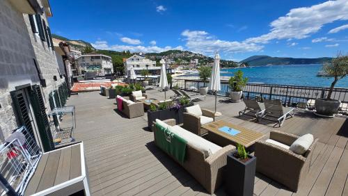 een terras met banken en stoelen aan het water bij Tamaris Apartmani in Herceg-Novi