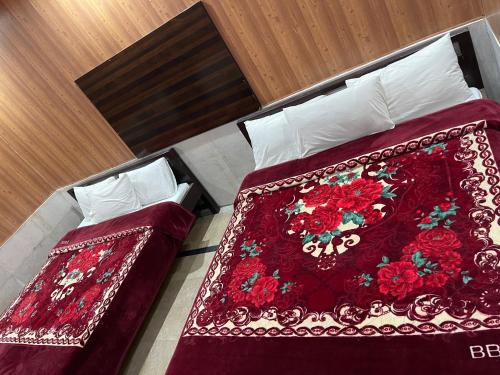 - 2 lits dans une chambre d'hôtel avec une couverture rouge dans l'établissement All khair hotel, à Murree