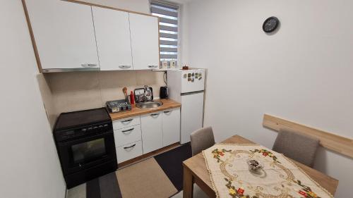 a small kitchen with white cabinets and a table and a table and a tableablish at Sabina apartmani in Tuzla