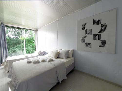 a white bedroom with two beds and a window at Casa Container Moderna com Vista da Natureza em Itajaí in Itajaí