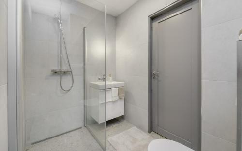 a white bathroom with a shower and a sink at Lodja Suites in Tartu